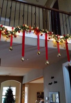 christmas decorations hanging from the banisters in a living room with red ribbon on them