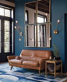 a living room with blue walls and leather furniture in the center, along with large mirrors on the wall