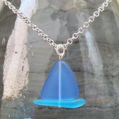 a necklace with a blue glass piece hanging from it's side on a chain