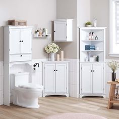 a bathroom with white cabinets, toilet and shelves on the wall next to each other