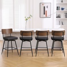 three chairs sitting in front of a white table with a vase on top of it