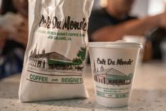 a coffee bag and cup sitting on a counter next to each other in front of a person