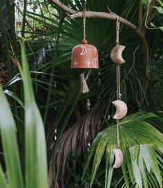 a wind chime hanging from a tree with moon and crescents painted on it