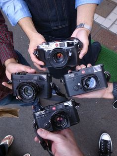 four people holding up cameras in their hands