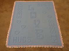 a crocheted baby blanket with numbers and letters on the bottom, in pink and blue