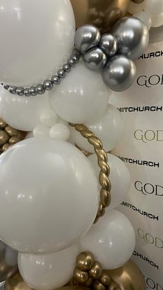 white and silver balloons are on display in a room with gold foiled letters that spell out the word god