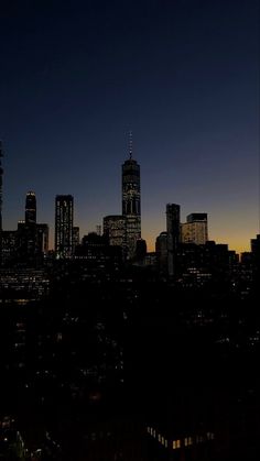 the city skyline is lit up at night, with skyscrapers in the foreground