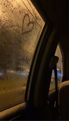 the back window of a car with graffiti on it's glass and raindrops