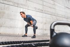 a man in grey shirt and black leggings doing push ups on a rope