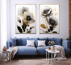 two paintings on the wall above a blue couch in a living room with wooden floors