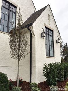 a white brick house with black trim and two large windows on the side of it