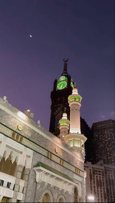 a clock tower in the middle of a city at night with lights on it's sides