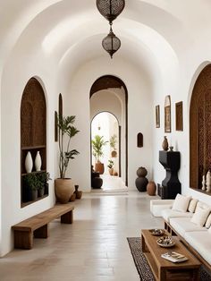 a living room filled with white furniture and lots of potted plants on the wall