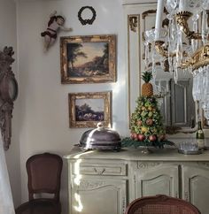 a dining room with an antique buffet and chandelier hanging from the ceiling above it