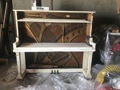 an old piano sitting on top of a table next to other pieces of wood and plastic