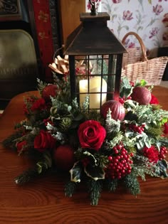 a lantern is sitting on top of a table with flowers, berries and greenery