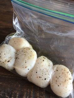 some kind of food in a plastic bag on a wooden table with water and seasoning