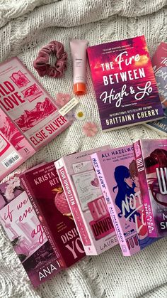 there are many books on the bed with pink covers and scarves next to them