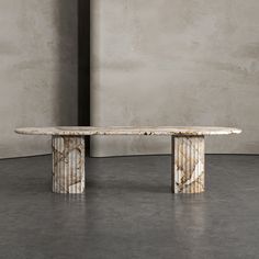 a marble table sitting on top of a cement floor next to a brick wall in an empty room