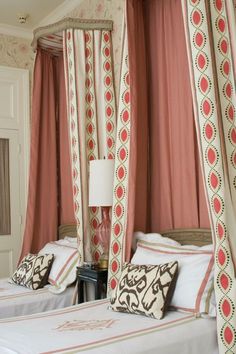 two beds in a room with pink curtains