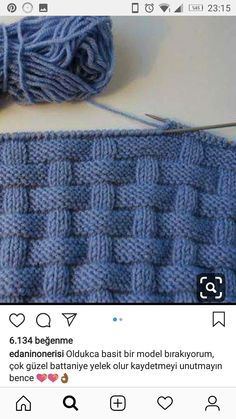 a blue knitted blanket next to a ball of yarn