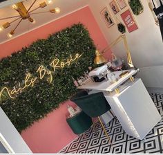 the interior of a nail salon with pink walls and green plants on the wall behind it