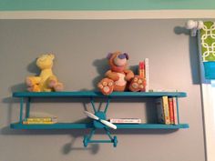 a blue shelf with two teddy bears on it and bookshelves above the shelves