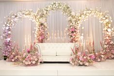 a white couch sitting in front of a flower covered stage with flowers on the wall