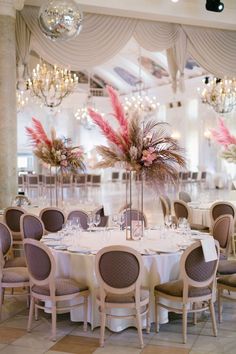 the tables are set with white linens and tall centerpieces filled with pink flowers