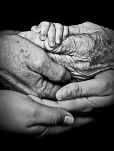 two hands holding an older hand in black and white, while another holds the younger hand