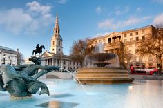 a fountain with a horse and rider statue in front of a large building on the other side