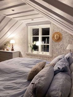 a bed with two pillows on top of it in a bedroom next to a window