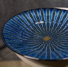 a blue and black plate sitting on top of a white table next to a gray wall