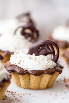 some cupcakes with chocolate frosting and whipped cream on top are sitting next to each other