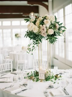 a tall centerpiece with white flowers and greenery