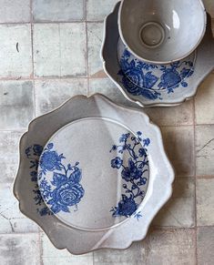 two blue and white dishes sitting on top of a tiled floor next to each other