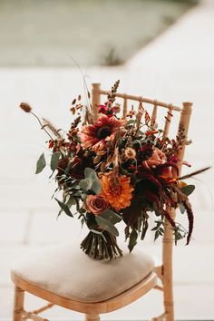 an arrangement of flowers is sitting on a chair