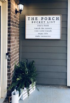 the porch bucket list sign in front of a brick building with potted plants outside