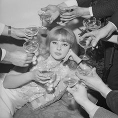 a group of people holding wine glasses in front of each other with their hands on top of the woman's head