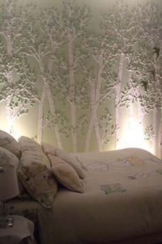 a bed sitting in front of a wall with trees on it