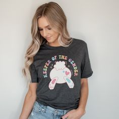 Get ready to reveal the gender of your little bundle of joy with this fun and festive Keeper of the Gender shirt! Our Easter gender reveal party shirt is perfect for expecting parents who want to share the exciting news with friends and family in a creative and memorable way. All of our adult t-shirts are Bella + Canvas 3001 Unisex shirts. They are a super soft fabric that will quickly become a go to in your wardrobe. Its lightweight and flexible material is perfect for casual wear or any activi Cute Crew Neck Tops For Gender Reveal, Cute Cotton Shirt For Gender Reveal, Playful Graphic Print Tops For Gender Reveal, Unisex Tops With Funny Print Gift, Fun Crew Neck Top For Gender Reveal, Gender Reveal Graphic Tee With Short Sleeves, Gender Reveal Graphic Tee Shirt With Short Sleeves, Cute Tops With Funny Text For Gender Reveal, Playful Short Sleeve Tops For Gender Reveal