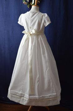 Maria Classic communion dress beautifully hand crafted with fine swiss cotton. Simple yet elegant with hues of ivory and white. Exquisite embellishment of fine hand embroidered shadow work. The center bodice of this georgeous communion dress is decorated with hand embroidered Classic First Communion Dress With Lace Trim, White Fitted Bodice First Communion Dress With Short Sleeves, First Communion Dress With Lace Trim, Classic White Baptism Dress With Fitted Bodice, Classic Dresses With Fitted Bodice For First Communion, Classic Cream Confirmation Dress, Classic Cream Dress For Confirmation, Classic White First Communion Dress, White Gown With Fitted Bodice For First Communion