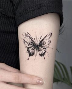 a woman's arm with a black and white butterfly tattoo on the left side