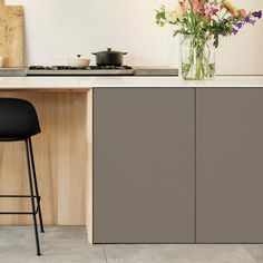 a vase with flowers sitting on top of a kitchen counter next to a bar stool