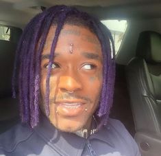 a man with purple dreadlocks sitting in a car