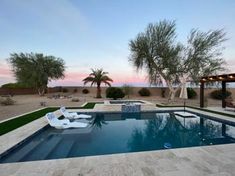 an outdoor pool with lounge chairs and palm trees