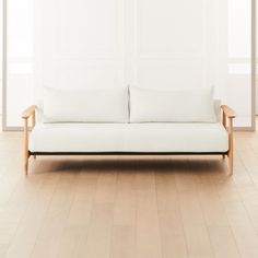 a white couch sitting on top of a hard wood floor next to a wooden frame