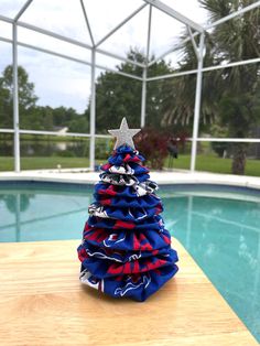 a small christmas tree sitting on top of a wooden table next to a swimming pool