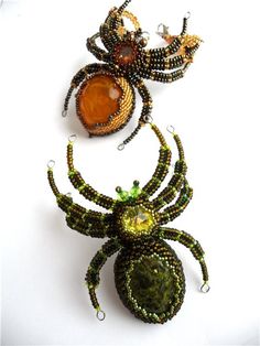 three beaded spider brooches sitting next to each other on a white surface