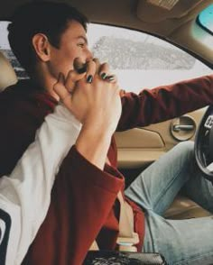 a man sitting in the driver's seat of a car with his hands clasped